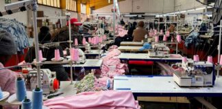 Workers operate sewing machines while others sit idle in a South African clothing factory.