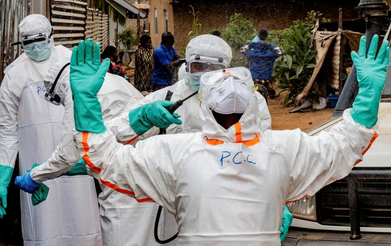 Civil Protection team members in personal protective equipment disinfect an area after handling the body of a man who died of Ebola in Bunia, Democratic Republic of Congo.