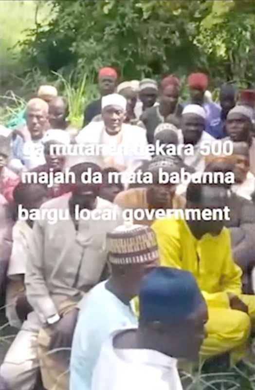Abducted women, children, and older people sitting on grass in a social media video from Niger State, Nigeria.