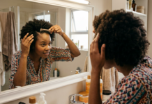 A Black South African woman with healthy afro-textured hair examining her scalp.